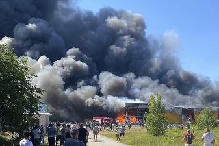 Ľudia sledujú, ako sa valí dym z preplneného nákupného centra v Kremenčuku po tom, ako bolo zasiahnuté ruskými raketami.
