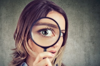 Curious young woman looking through a magnifying glass