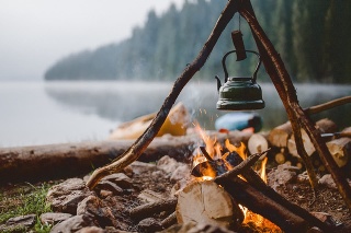 Campfire with a vintage kettle next to the beautiful lake.