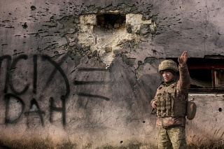 Ukrajinský príslušník ozbrojených síl ukazuje na smer prichádzajúceho ostreľovania vedľa budovy, ktorá bola v sobotu 19. februára 2022 zasiahnutá mínometným granátom veľkého kalibru v frontovej dedine Krymske v Luhanskej oblasti na východe Ukrajiny.