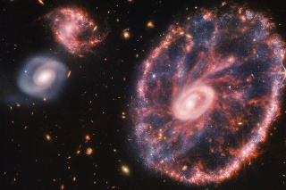 Vpravo sa nachádza veľká ružová škvrnitá galaxia, ktorá pripomína koleso a v jej vnútri sa nachádza menší ovál obklopený prachom modrej farby, vľavo sú viditeľné dve špirálové galaxie približne rovnakých rozmerov.