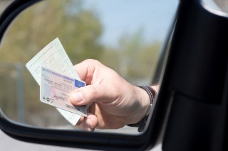 Ein Mann zeigt Führerschein und Fahrzeugschein bei einer Kontrolle