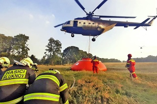 Mi-171 naberá vodu z nádrže na lúke.
