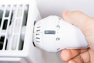 Male Hand Turns The Radiator Of A White Heater In The Living Room, Saving Energy Concept