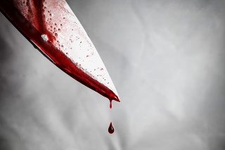 close-up of man holding knife smeared with blood and still dripping.