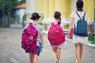 Three young girls are walking in the school yard at first day at school