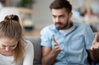 Upset wife sit on couch crying listening to furious husband yelling, unhappy couple have fight or disagreement at home, sad woman feel desperate and down with mad spouse scolding and lecturing