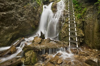 A technically aided trail along a waterfall in a lush gorge in Slovensky Raj in Slovakia.