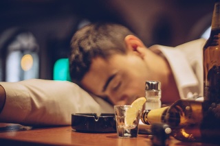 Young drunk man sleeping on bar counter in pub