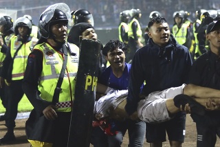 Fanúšikovia nesú zraneného muža po potýčkach na futbalovom zápase.