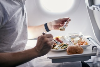 Passenger eating airline meal. Menu in business class on medium haul flight.