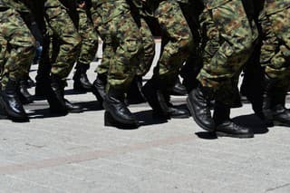 Army military soldiers marching in a parade outdoors.