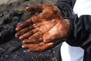 Cyklista ukazuje ruky špinavé od ropy na pláži Cavero v peruánskom okrese Ventanilla.