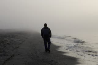 Lonely man walking on a foggy beach