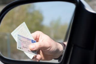 Ein Mann zeigt Führerschein und Fahrzeugschein bei einer Kontrolle