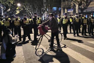Čínski policajti blokujú miesto, kde sa zhromažďujú demonštranti počas protestu proti covidovým opatreniam v čínskom Šanghaji