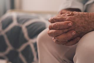 Cropped shot of a senior woman sitting with her hands clasped in a retirement home