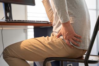 Japanese male businessman who suffers back pain from working from home