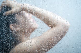 Women showering in the shower room close up with a water drop on glass door.