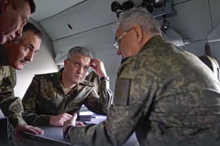 Ruský minister obrany Sergej Šojgu (vpravo) hovorí s dôstojníkmi na palube vojenského vrtuľníka na neznámom mieste na Ukrajine. 