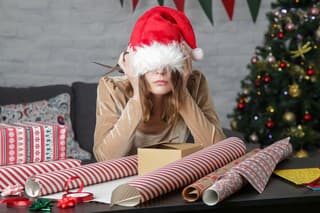 Depressed frustrated woman wrapping Christmas gift boxes, winter holiday stress concept