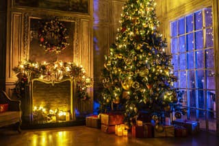 Christmas and New Year interior decoration. Green tree decorated with toys, gifts, present boxes, flashing garland, illuminated lamps. Fireplace and xmas tree. Cozy Christmas atmosphere