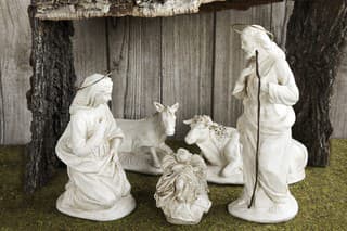 Christmas Manger scene with figurines including Jesus, Mary, Joseph, cow and mule on grass and wood background