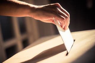 Conceptual image of a person voting, casting a ballot at a polling station, during elections.