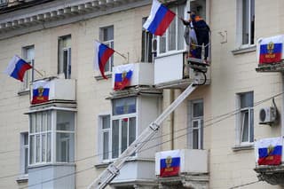 Robotníci vyvesujú ruské vlajky na bytovom dome v Luhansku na Ukrajine.