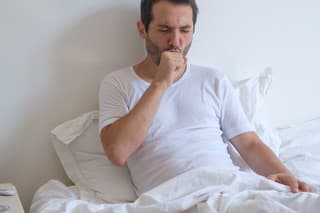 Sick man lying on bed and coughing a lot