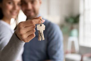 Close up happy woman hugging man, holding keys from new first house, young family celebrating moving day, satisfied customers couple purchase real estate, mortgage and relocation concept