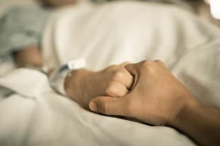 Man holding hand, giving support and comfort to woman, loved one sick in hospital bed.