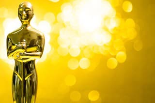 Golden statuette on shiny yellow background.