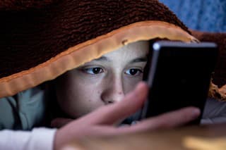 girl in bed texting on smartphone