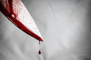 close-up of man holding knife smeared with blood and still dripping.