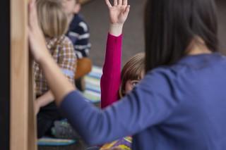 Kindergarten teacher and student with arm raised in classroom
