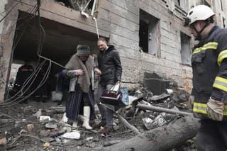 Muž pomáha vyjsť žene z obytnej budovy, ktorá sa stala terčom ruského ostreľovania v ukrajinskom meste Charkov v nedeľu 5. februára 2023. 