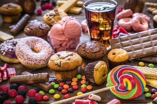 Assortment of products with high sugar level like candies, gummy candies, soda, donuts, chocolate, lollipop, wafers and cupcakes on rustic wooden table. Low key DSLR photo taken with Canon EOS 6D Mark II and Canon EF 24-105 mm f/4L