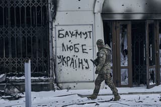 Ukrajinský vojak kráča po ulici okolo nápisu na stene 
