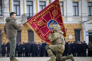 Zelenskyj s vlajkou vojenskej jednoty, ktorú bozkáva ukrajinský vojak.