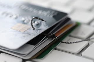 Fishing hook with credit cards on keyboard closeup. Cybercrime on internet concept