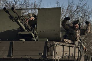 Ukrajinskí vojaci gestikulujú počas jazdy na armádnom vozidle v meste Bachmut v Doneckej oblasti.