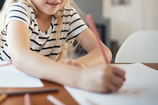 Cropped shot of an adorable little girl doing her homework at a table in the dining room