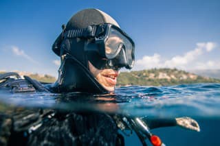 Portrait of scuba diver at sea surface preparing for dive underwater.