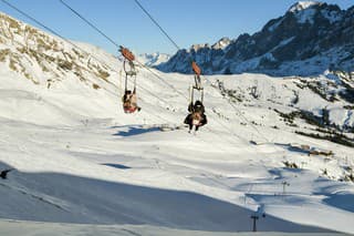 Grindelwald, Switzerland - December 30, 2019: Tourists riding down on First Flyer zipline attraction in mountains above Grindelwald, Switzerland during end of year 2019
