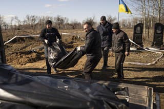 Muži odnášajú vrecia s telami obetí civilistov z nového pohrebiska, ktoré objavili v ukrajinskom meste Boroďanka 2. marca 2023. 