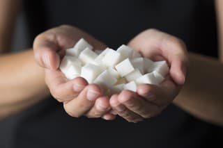 Caucasian female is holding sugar cubes in hand.
