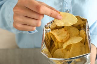 Woman eating tasty potato chips, closeup