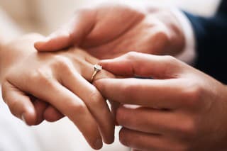 Cropped shot of an unrecognizable groom putting a diamond ring on his wife's finger during their wedding