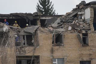 Príslušníci záchranných zložiek prehľadávajú trosky zničenej budovy po útoku dronu v meste Ržyščiv v Kyjevskej oblasti.